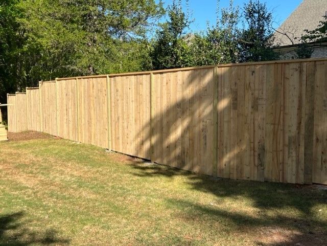a wooden fence is sitting on top of a lush green field