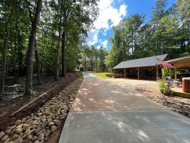 a driveway leading to a house in the woods