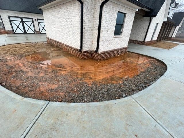 a corner of a house with a concrete walkway in front of it