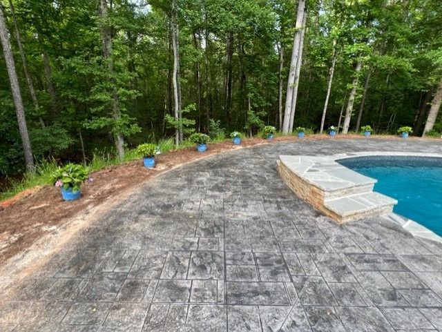 a patio next to a swimming pool with trees in the background