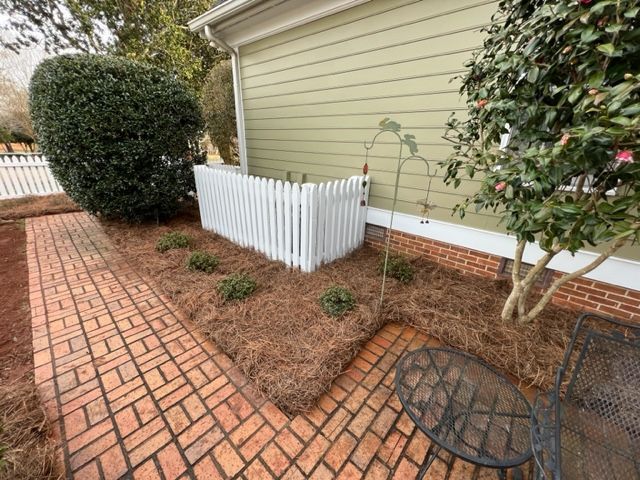 a brick walkway leading to a house with a white picket fence