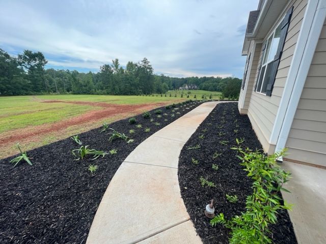 a concrete walkway leading to a house with a field in the background