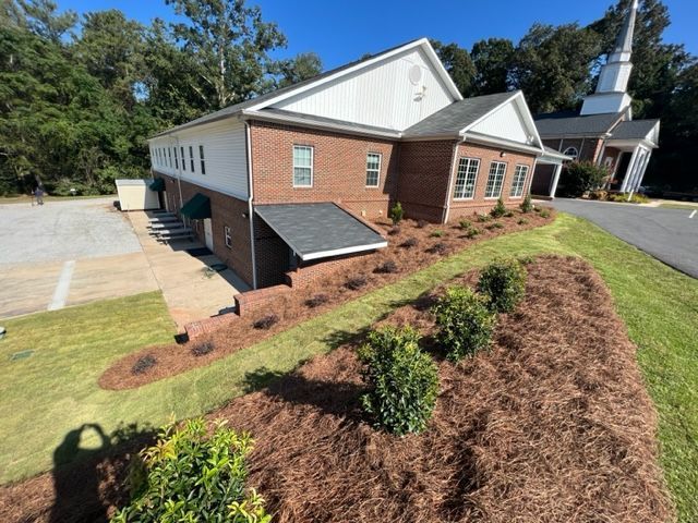 an aerial view of a church with a steeple in the background