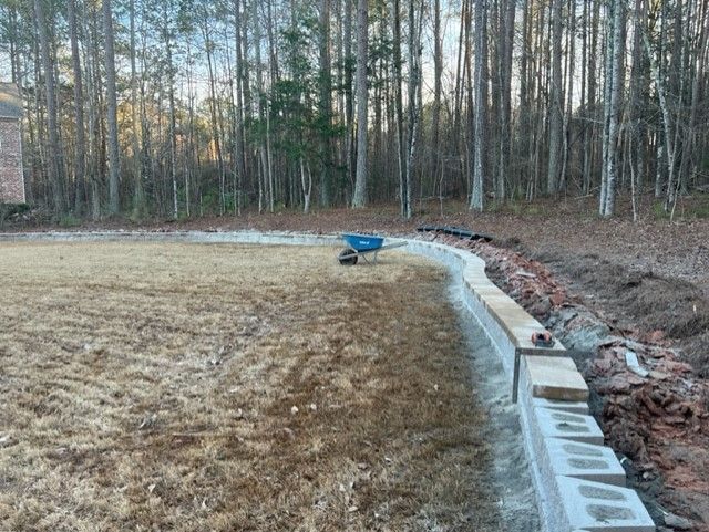 a concrete wall is being built in the middle of a field in the woods