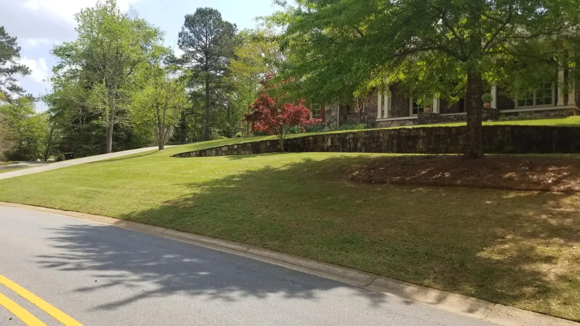 a lush green lawn along the side of a road next to a house