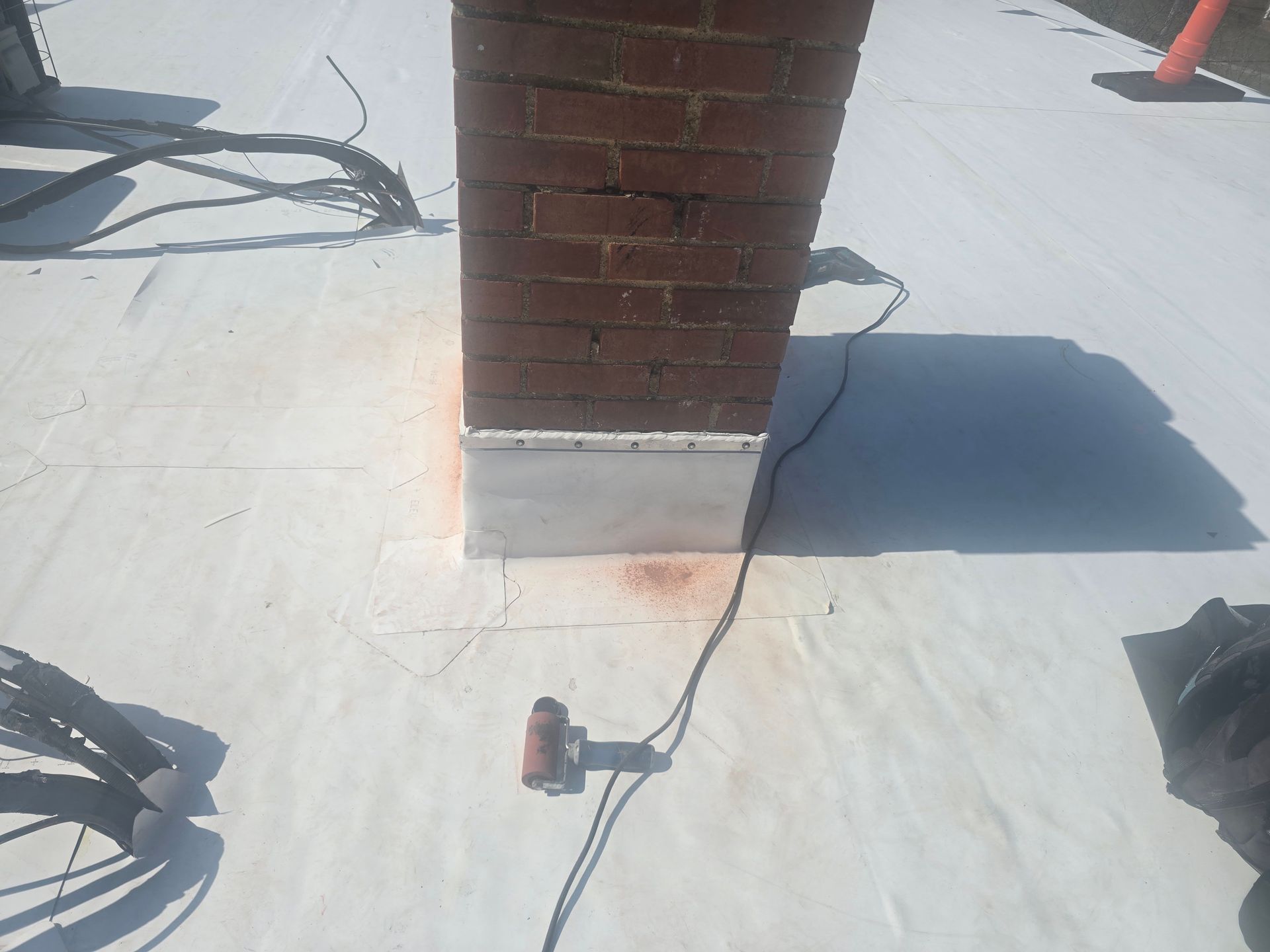 A brick chimney is sitting on top of a white roof.