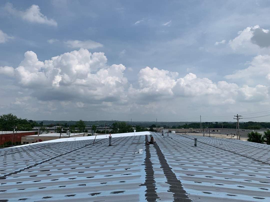The roof of a building with a blue sky and clouds in the background.