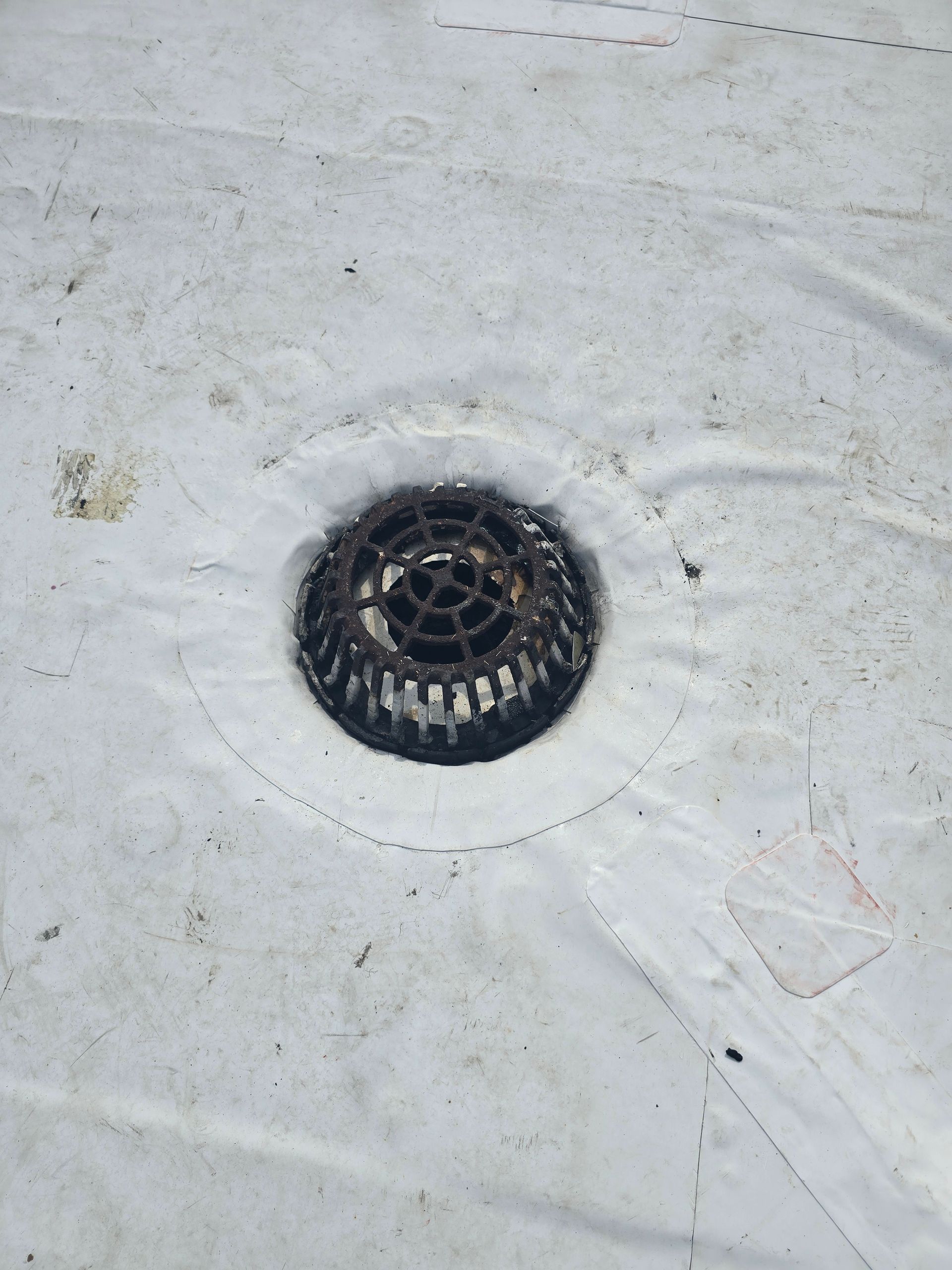 A close up of a drain hole on a white surface.