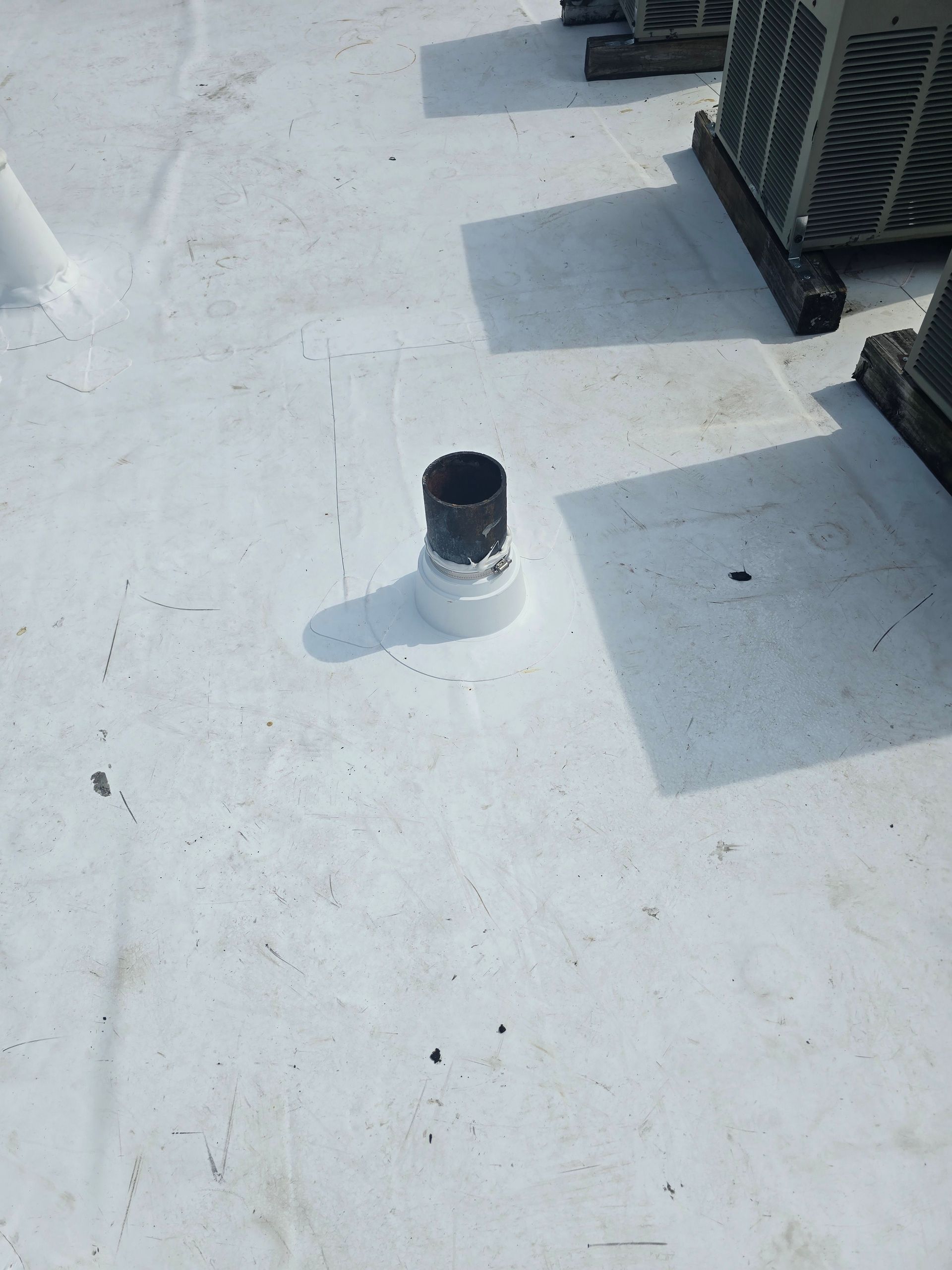 A white roof with a black pipe on it.