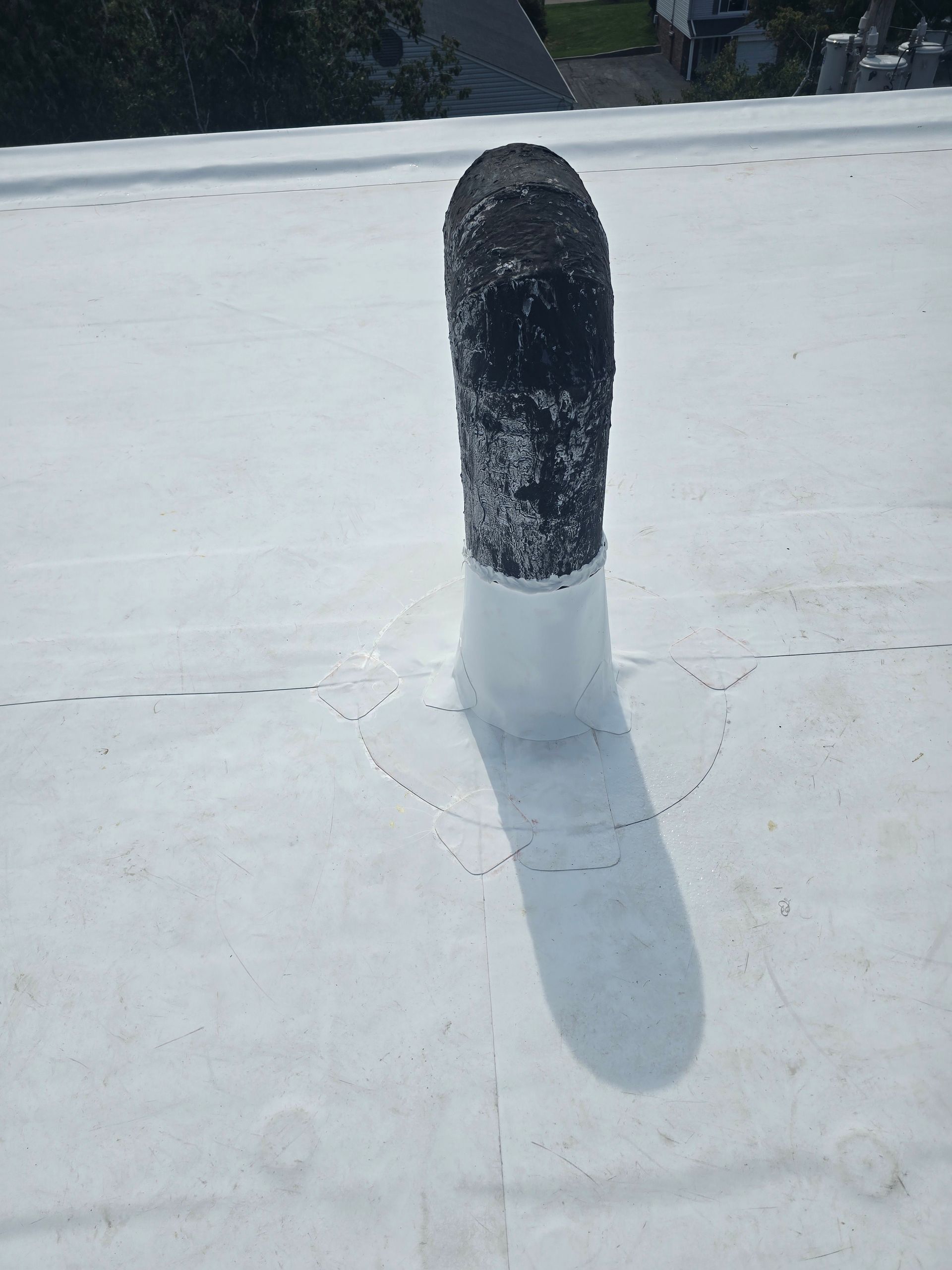 A black pipe is sitting on top of a white roof.