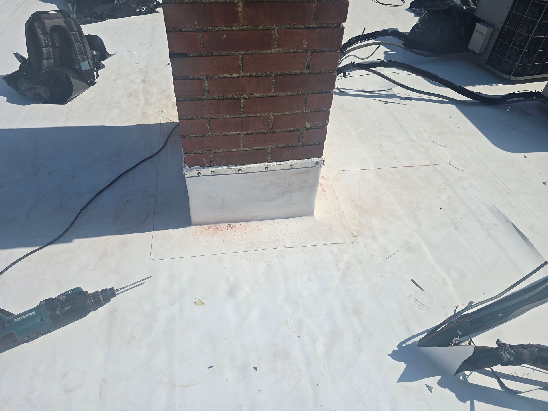 A brick chimney is sitting on top of a white roof.