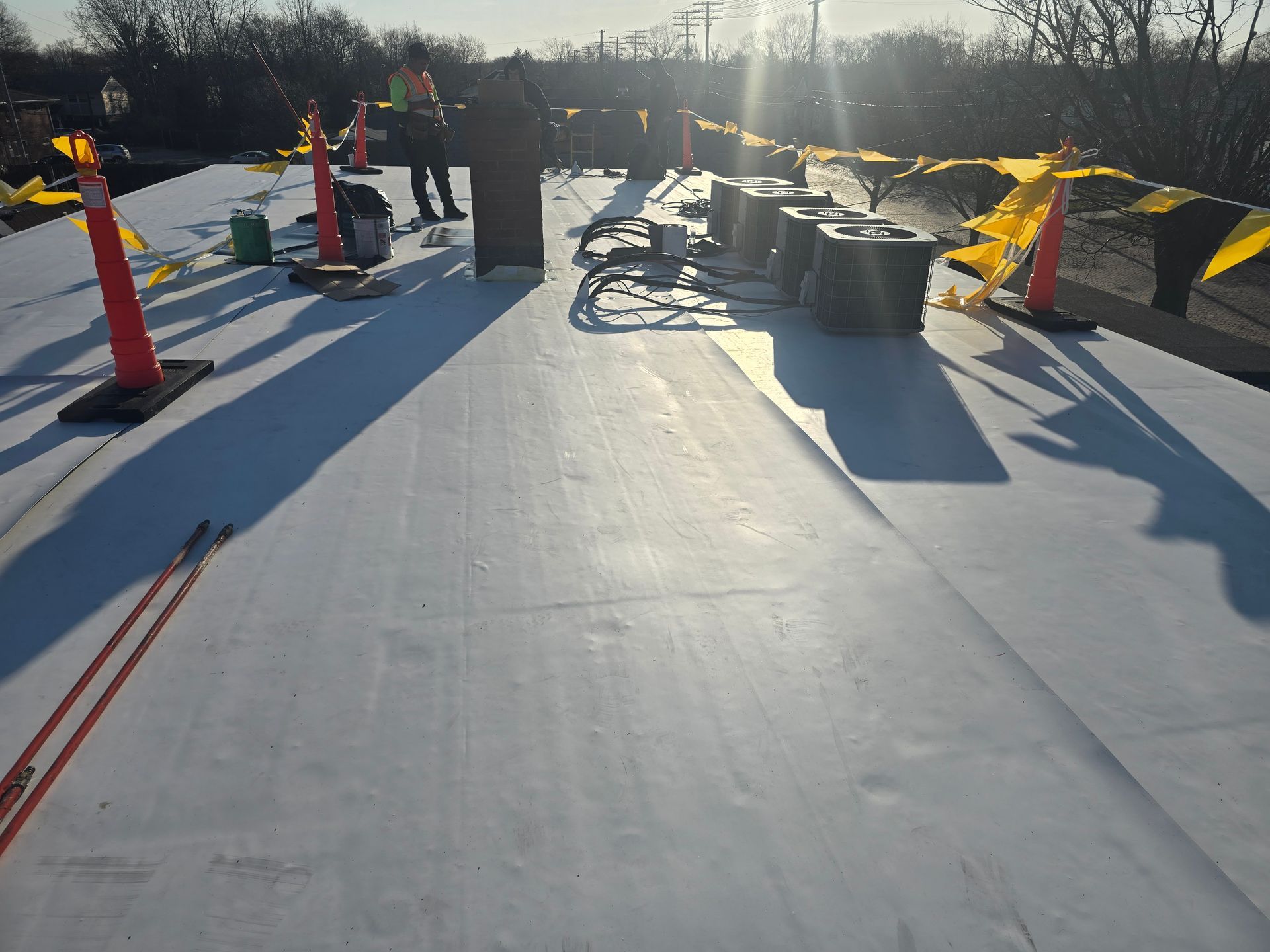 A group of construction workers are working on a white roof.