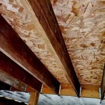 A close up of a ceiling made of plywood and wooden beams.