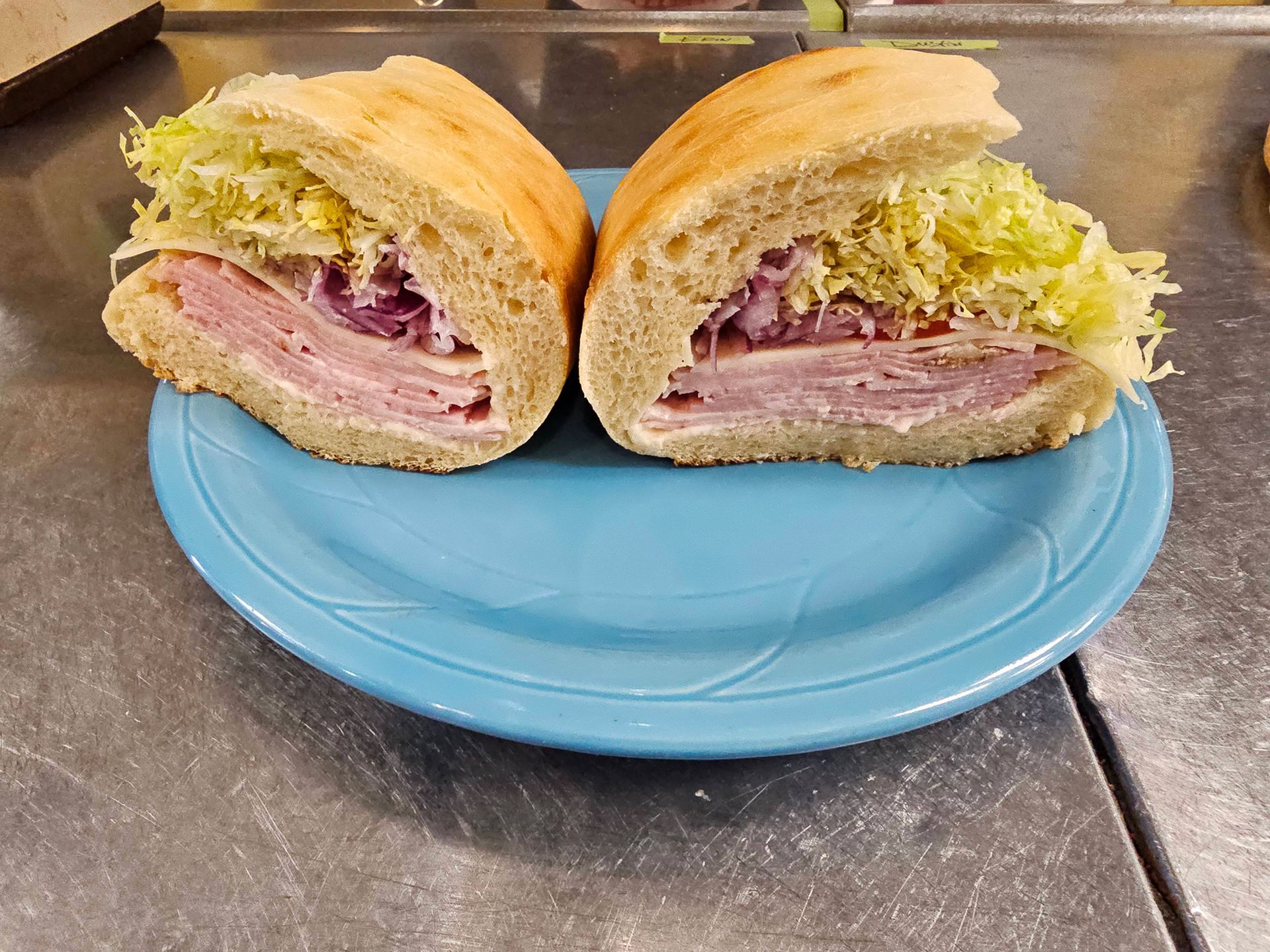 A sandwich is cut in half on a blue plate.