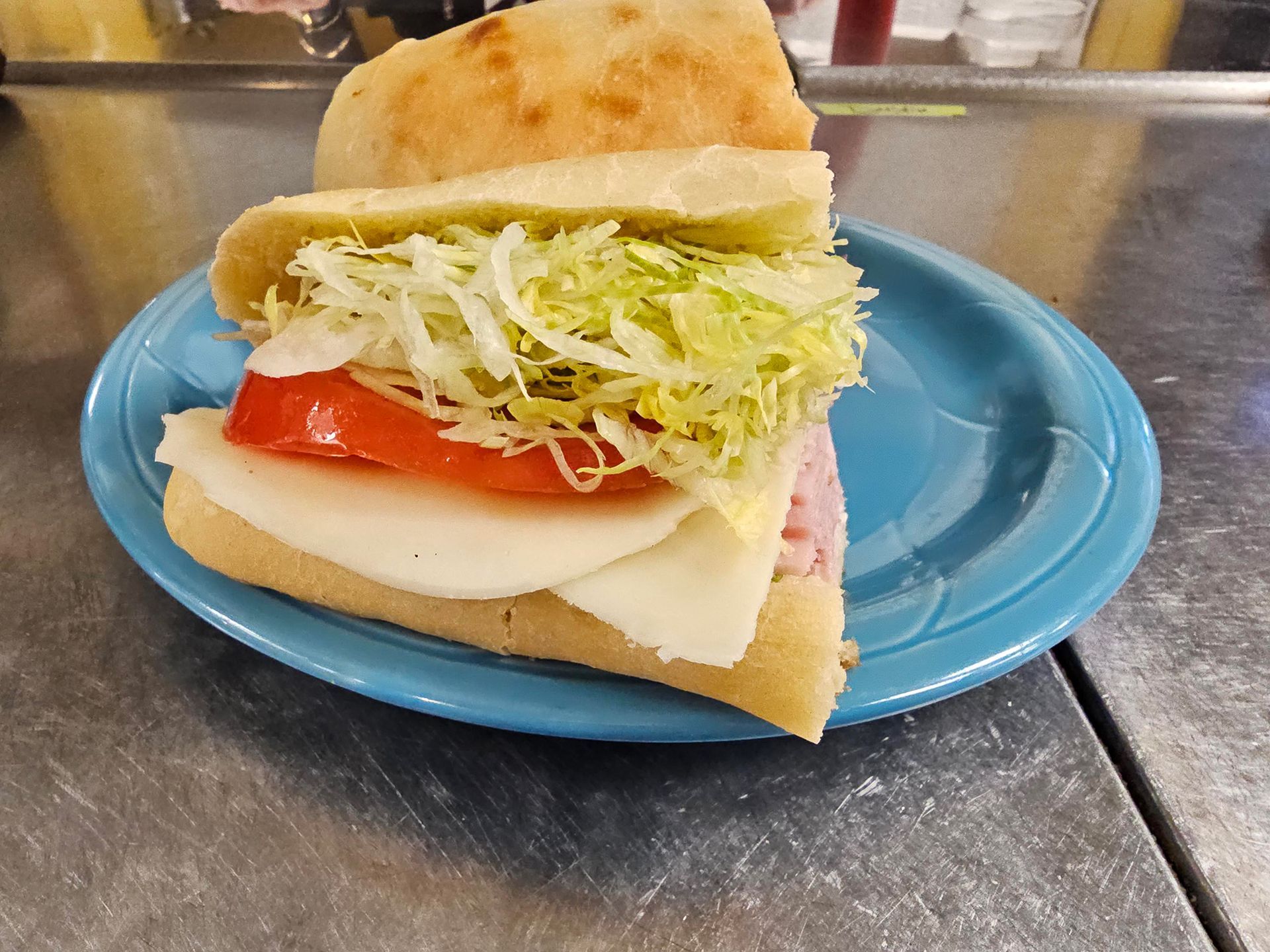 A sub sandwich on a blue plate on a table.