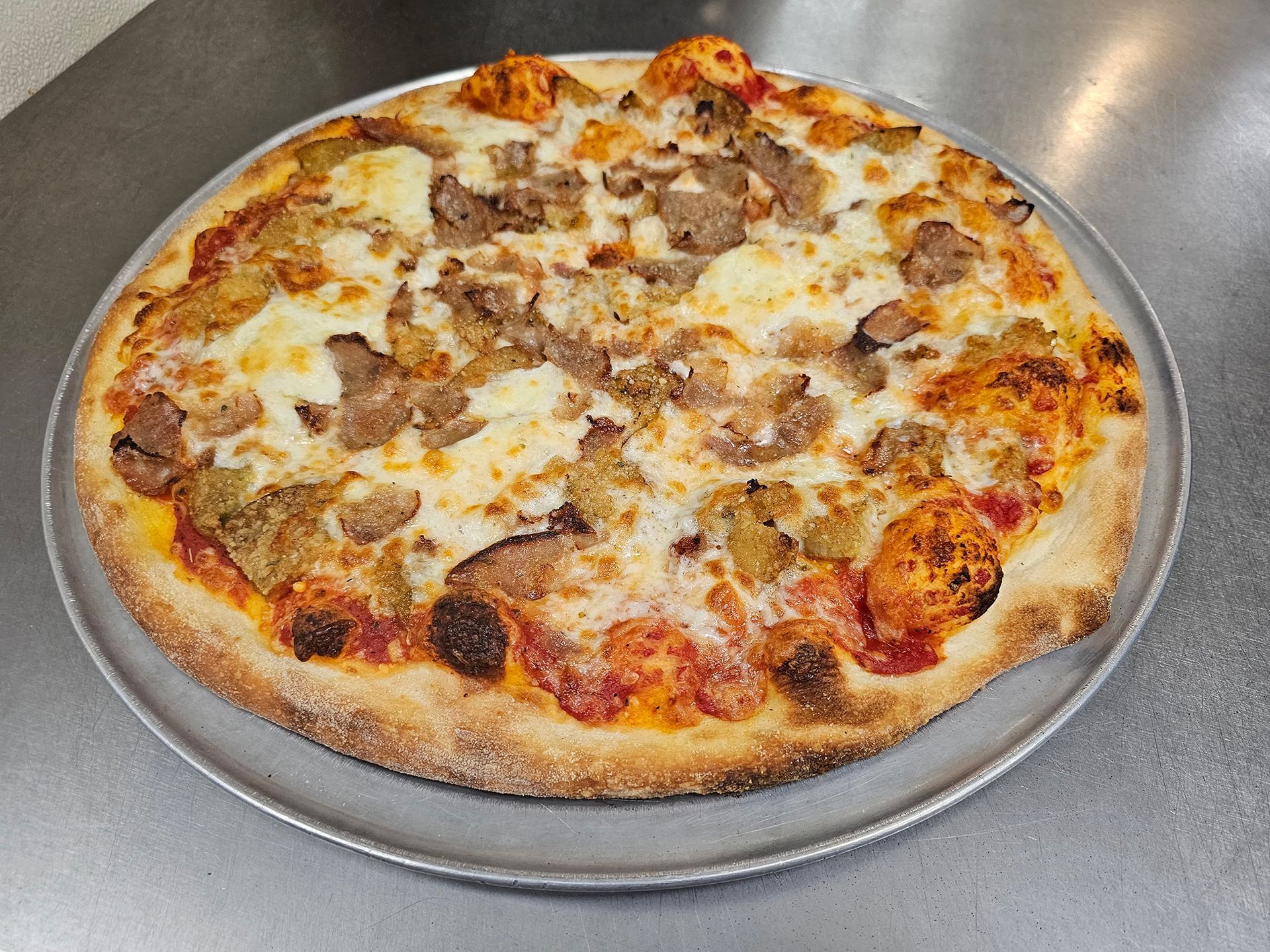 A pizza is sitting on a pan on a table.