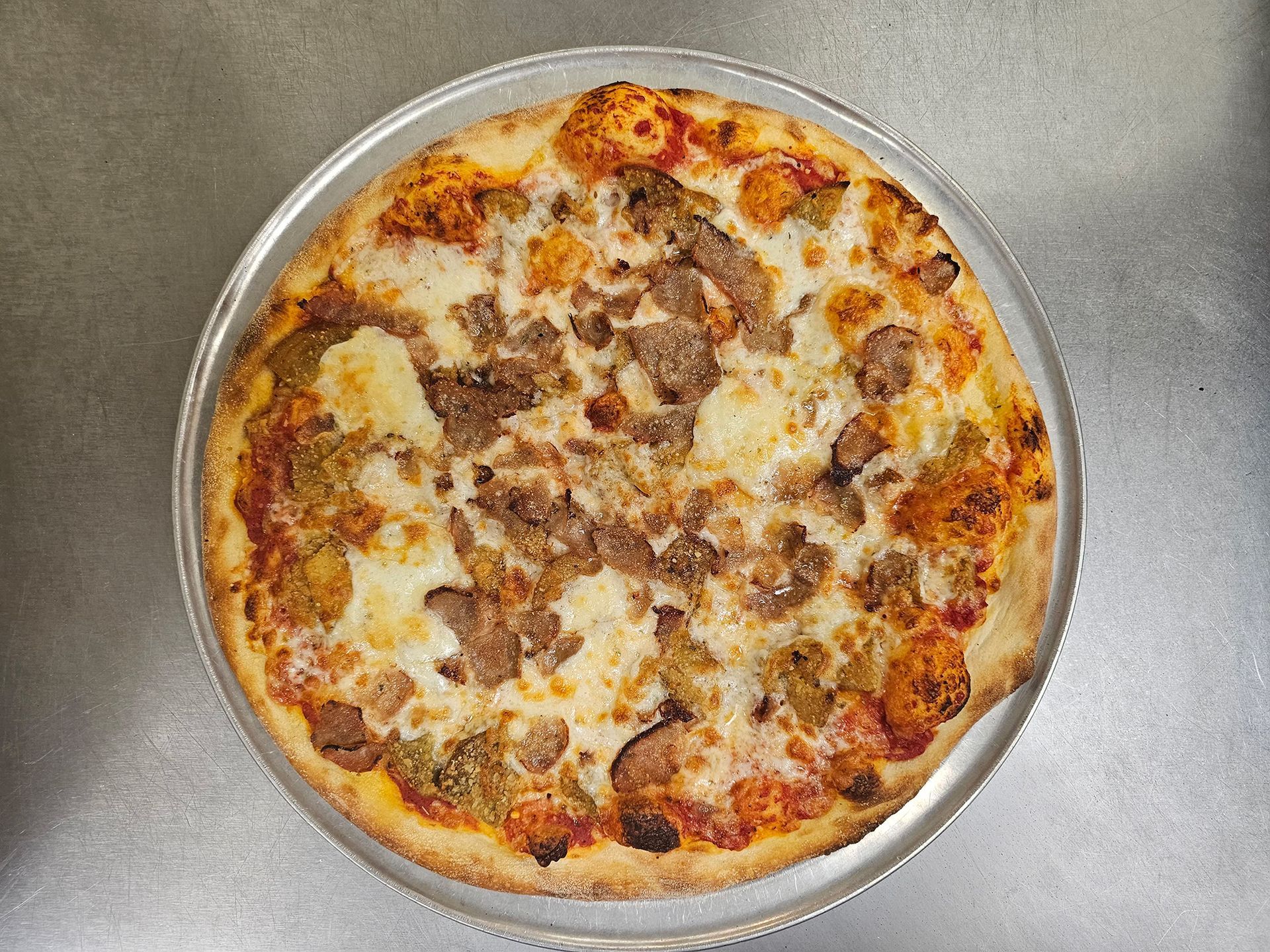 A pizza is sitting on a metal pan on a table.