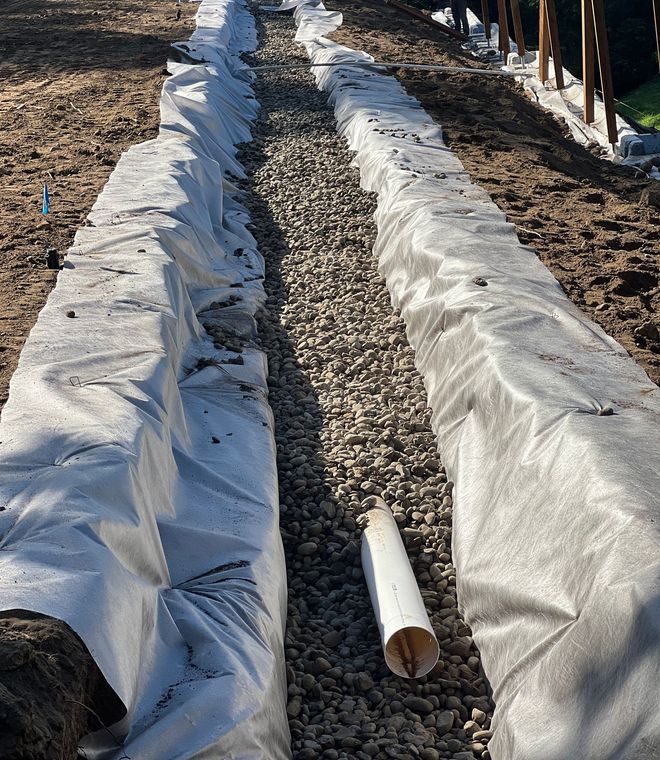 Grassy area with metal drainage grates set in concrete bordering the lawn.