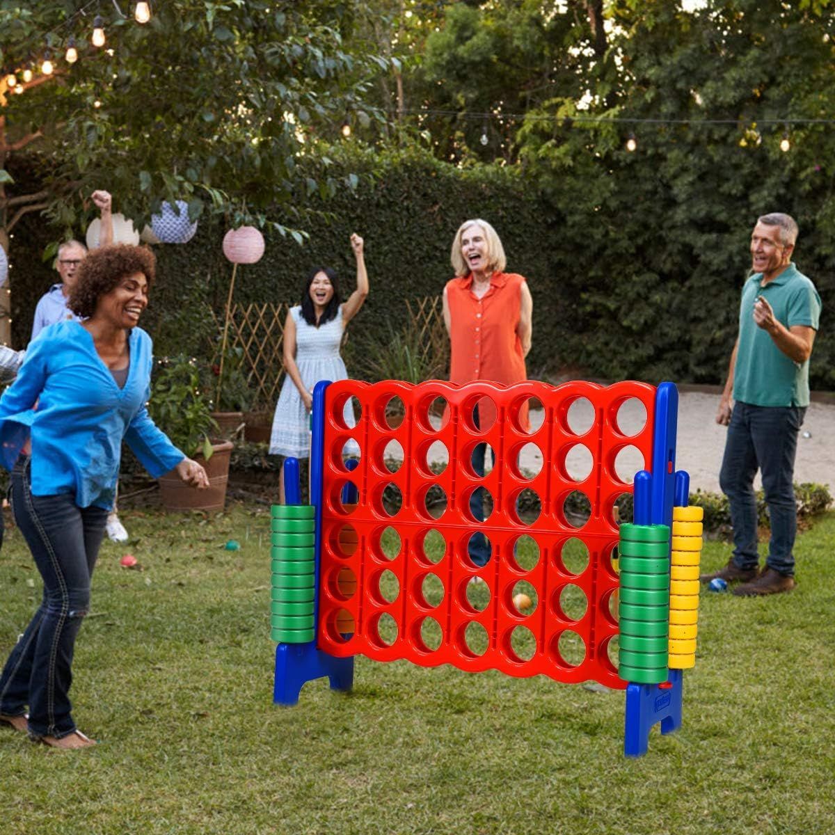 A group of people are playing a giant connect four game in a backyard.