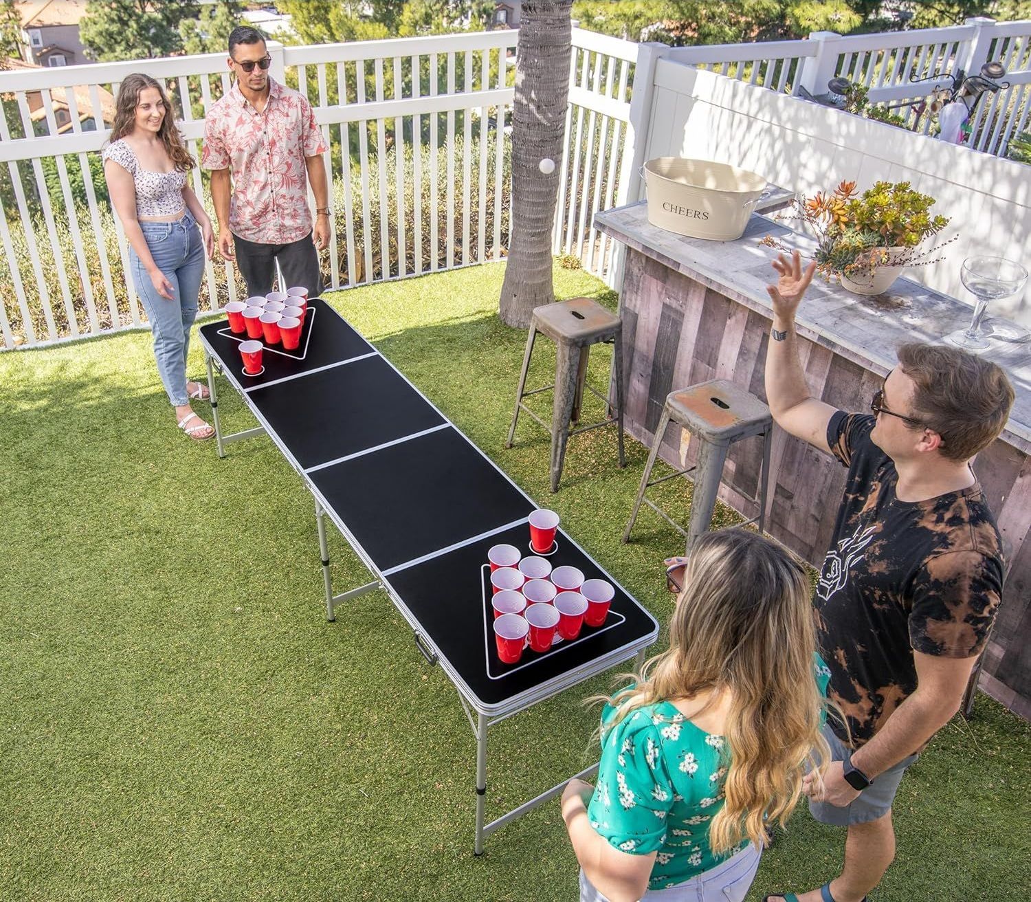 A group of people are playing beer pong on a table.