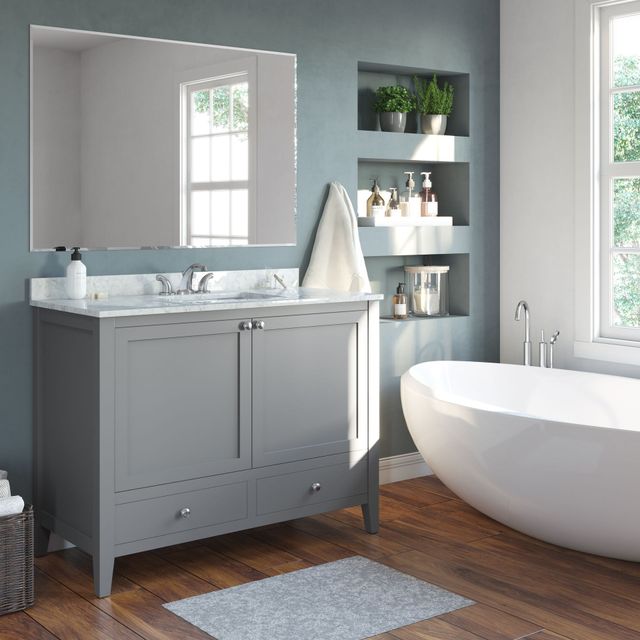 Modern gray bathroom with vanity, mirror, shelves, and a freestanding white tub by a window