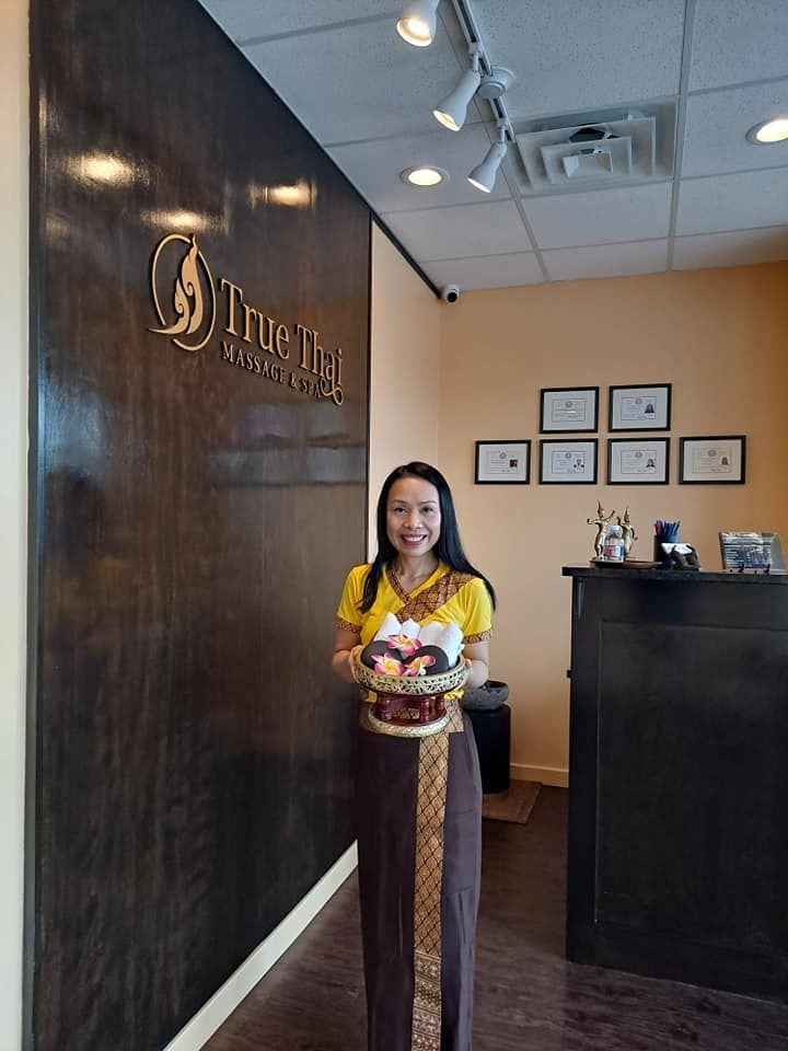 A woman is standing in front of a wall holding a basket of flowers.