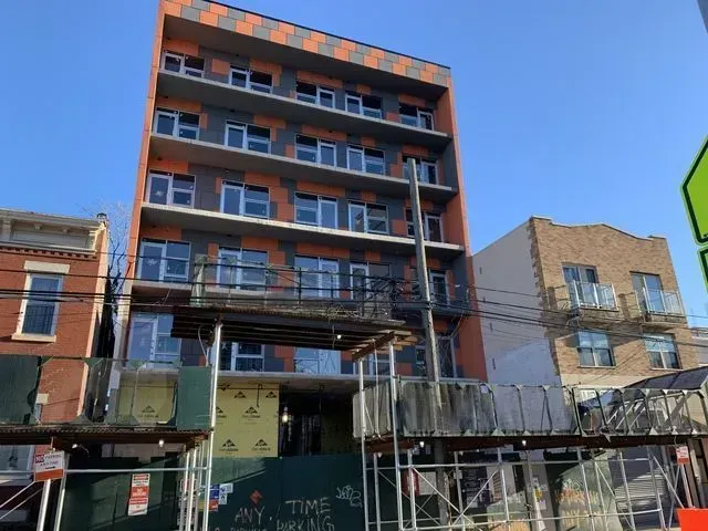 Partially built brick apartment building with scaffolding under a blue sky