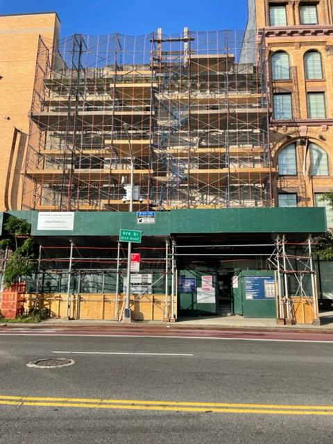 Scaffolded building facade with green construction awning on a city street