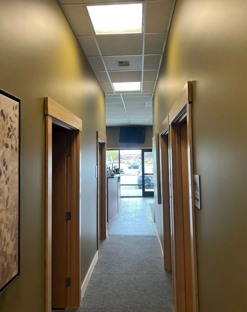 Industrial mechanical room featuring overhead insulated white pipes and large gray metal ventilation ducts.