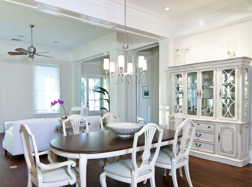 Solar panels mounted on the gray shingled roof of a house with light-colored siding and a white garage door.