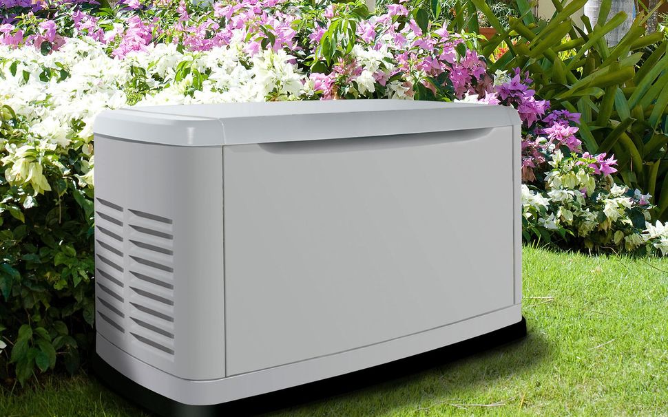 A red brick house with a dark tiled roof, solar panels, two dormer windows, and a grassy yard with trees.