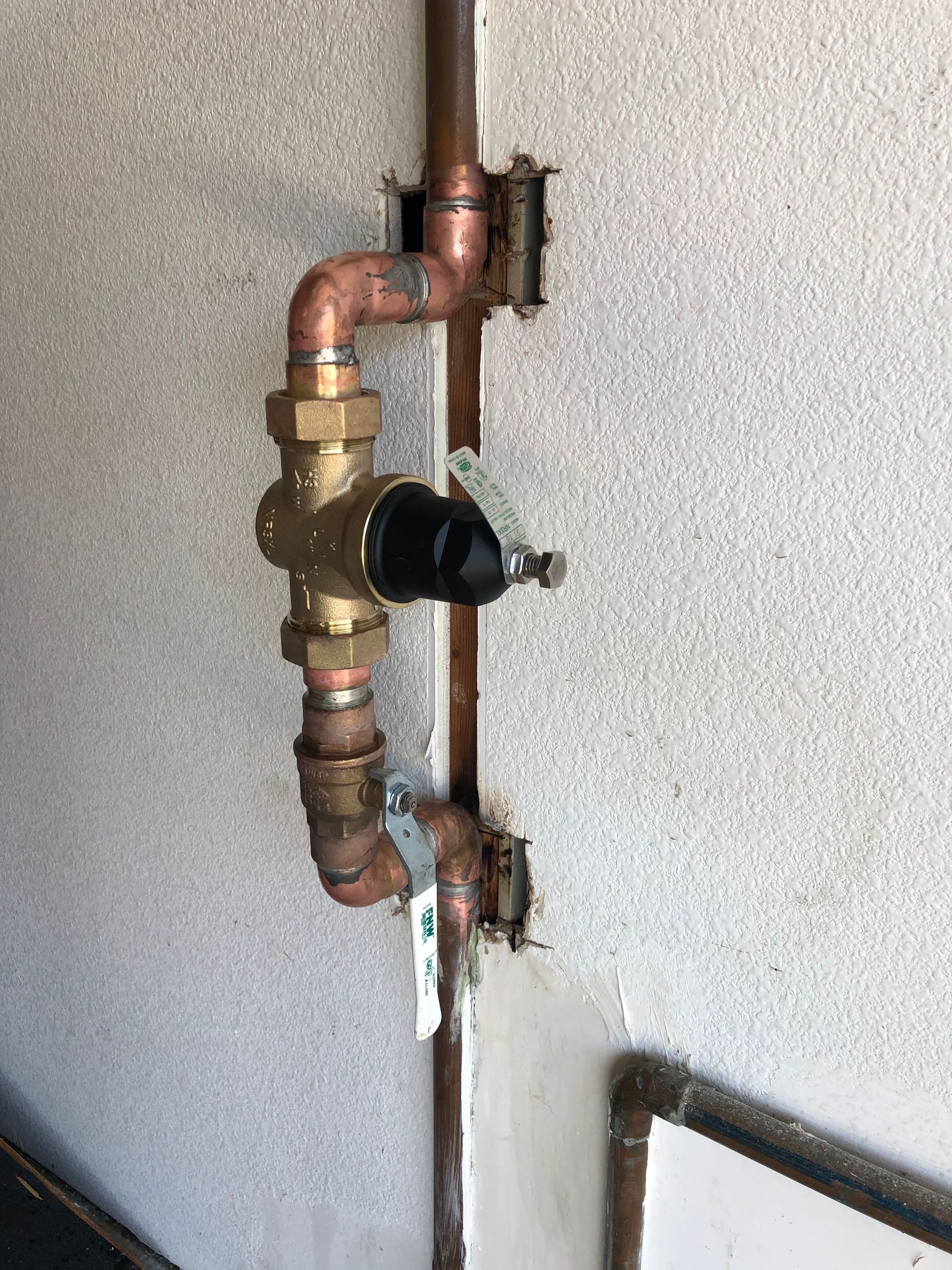 A close up of a copper pipe on a wall.