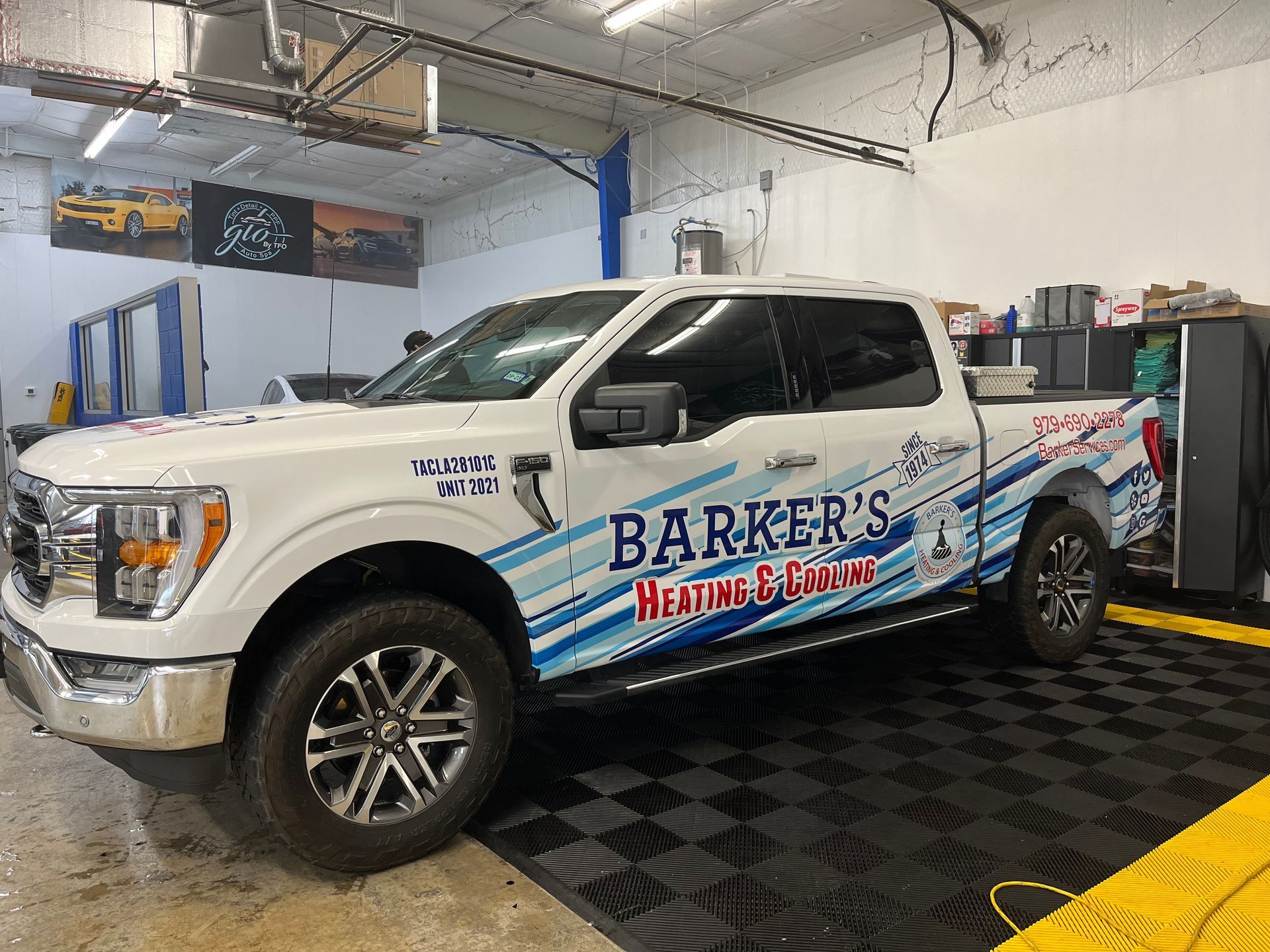 a white truck with a wrap on it is parked in a garage.