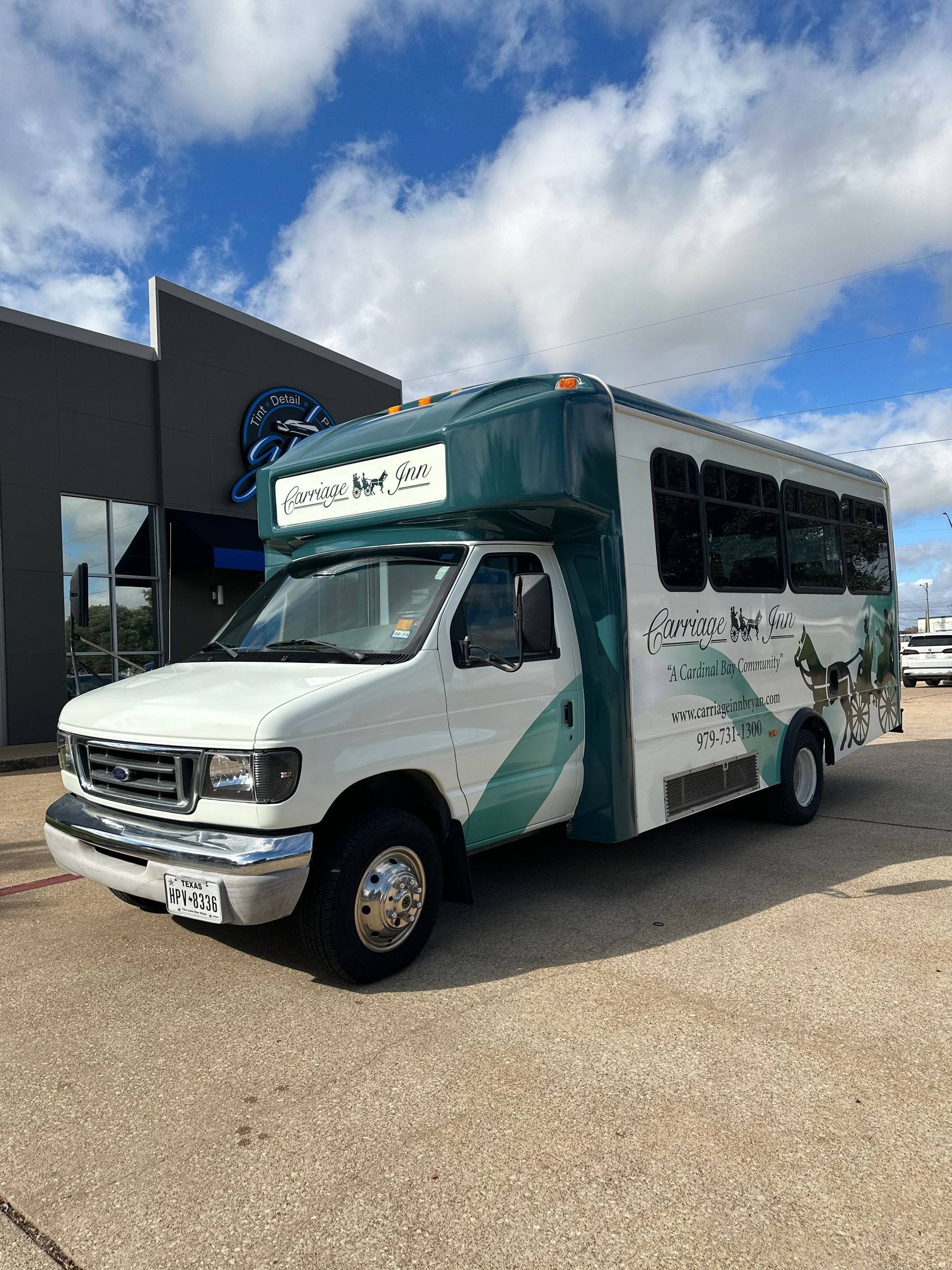 a white and green bus is parked in front of a building.