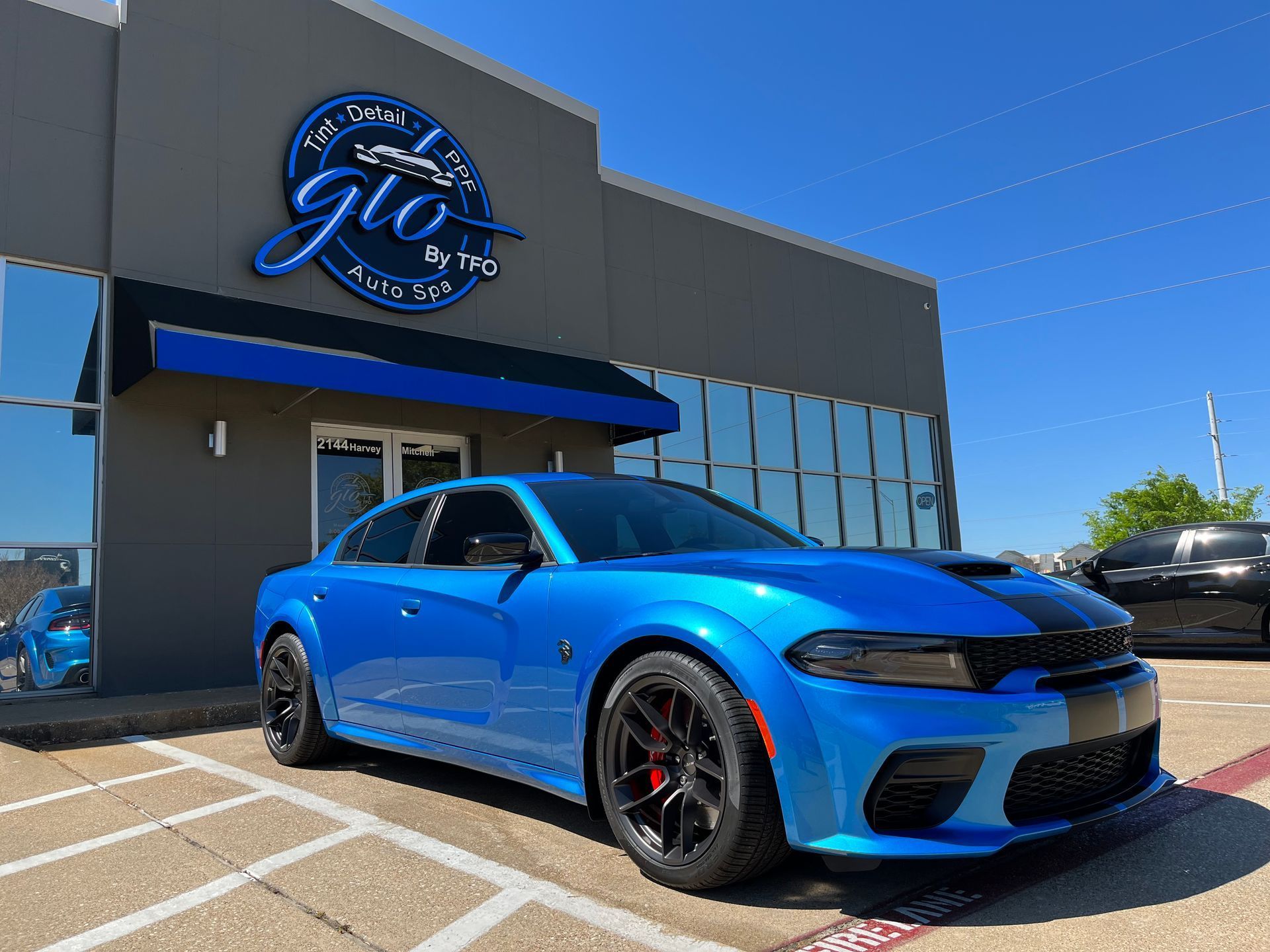 a blue dodge charger is parked in front of a building .