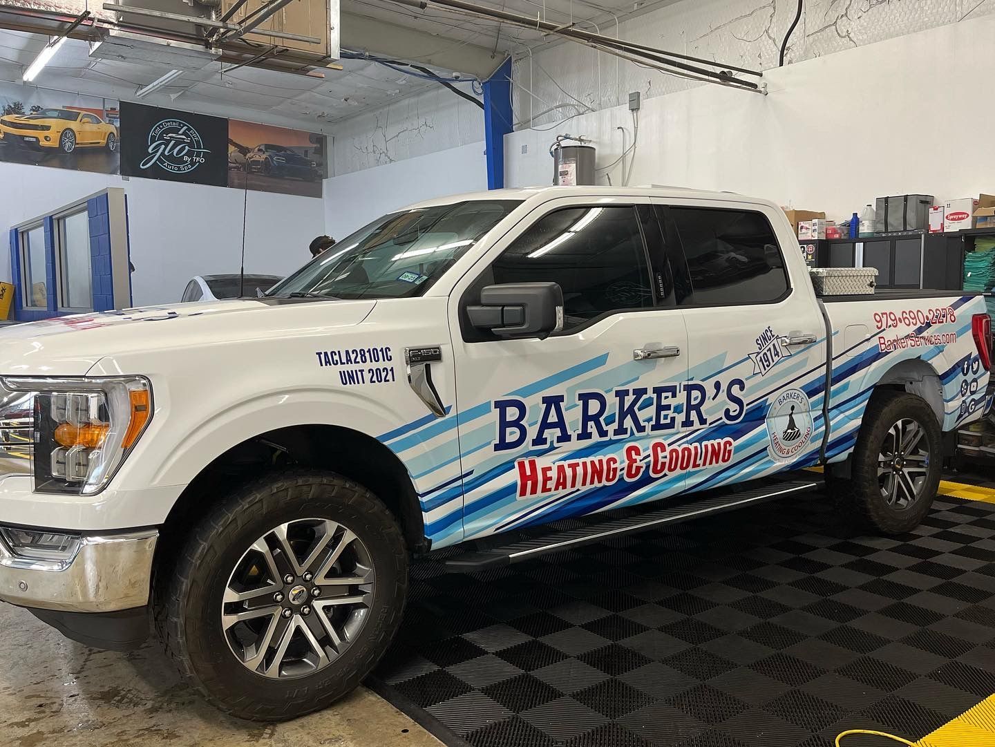 a white truck with barker 's heating and cooling written on the side is parked in a garage .