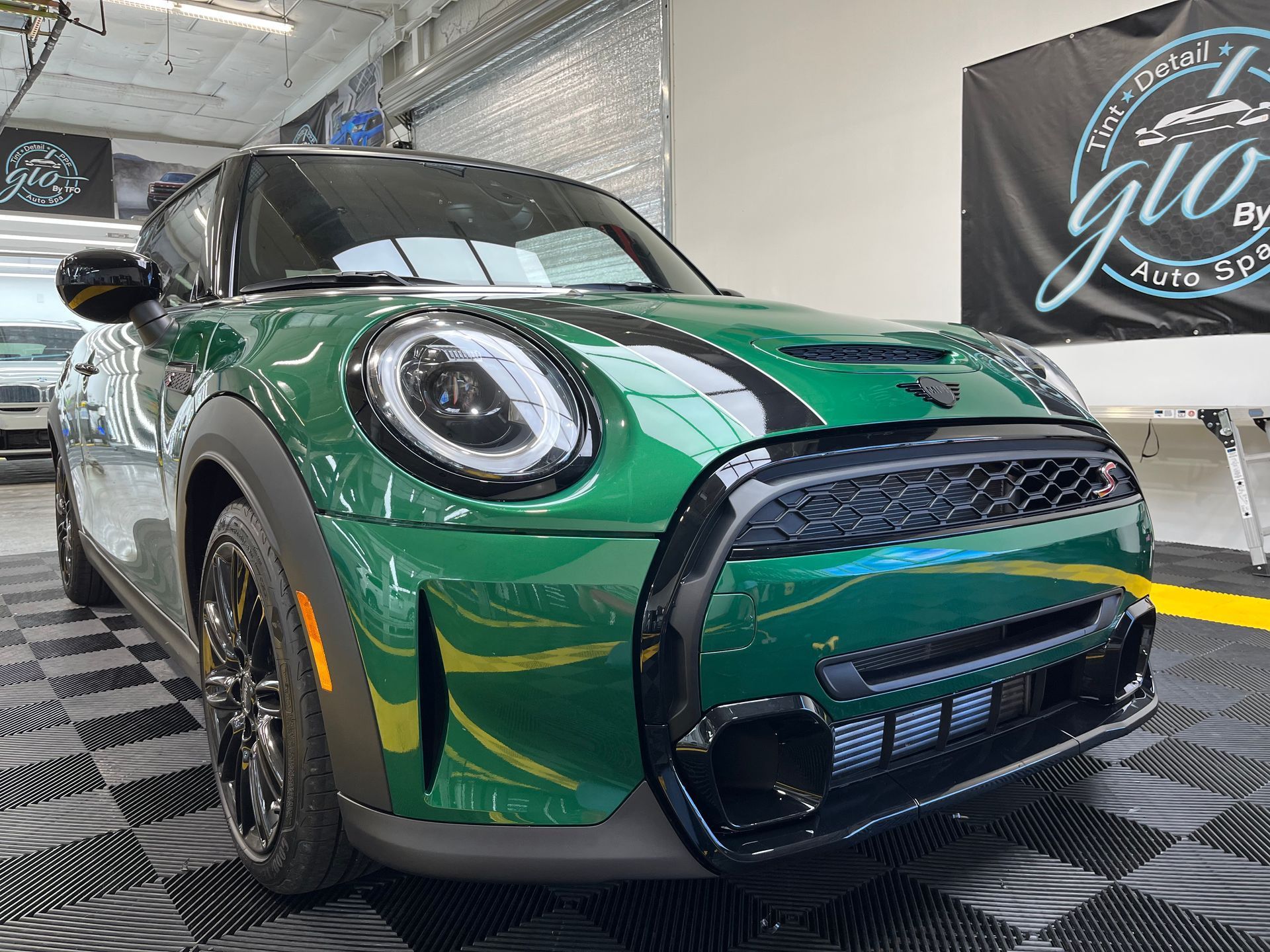 a green mini cooper s is parked in a garage .