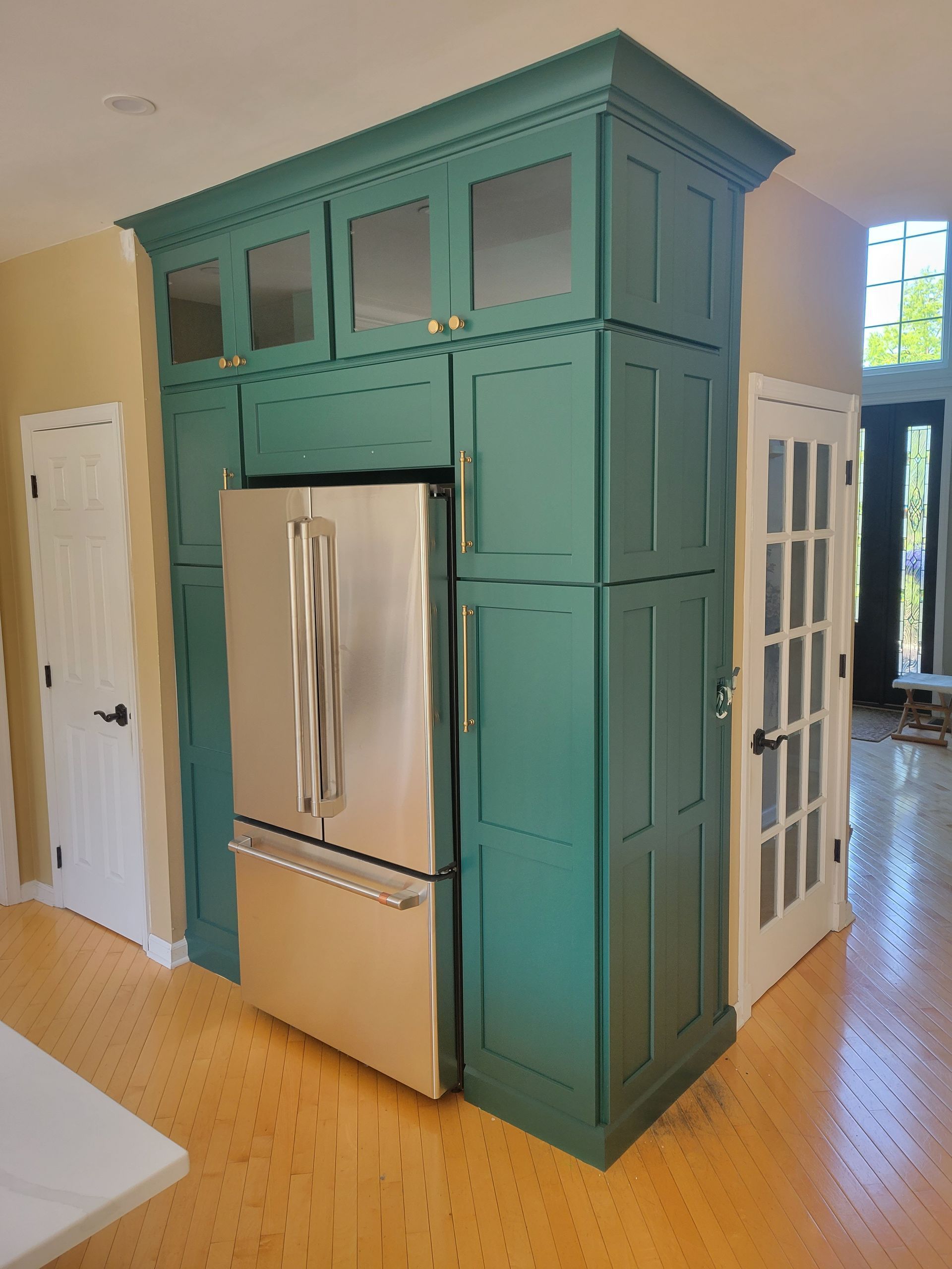 A kitchen with green cabinets and a stainless steel refrigerator - after