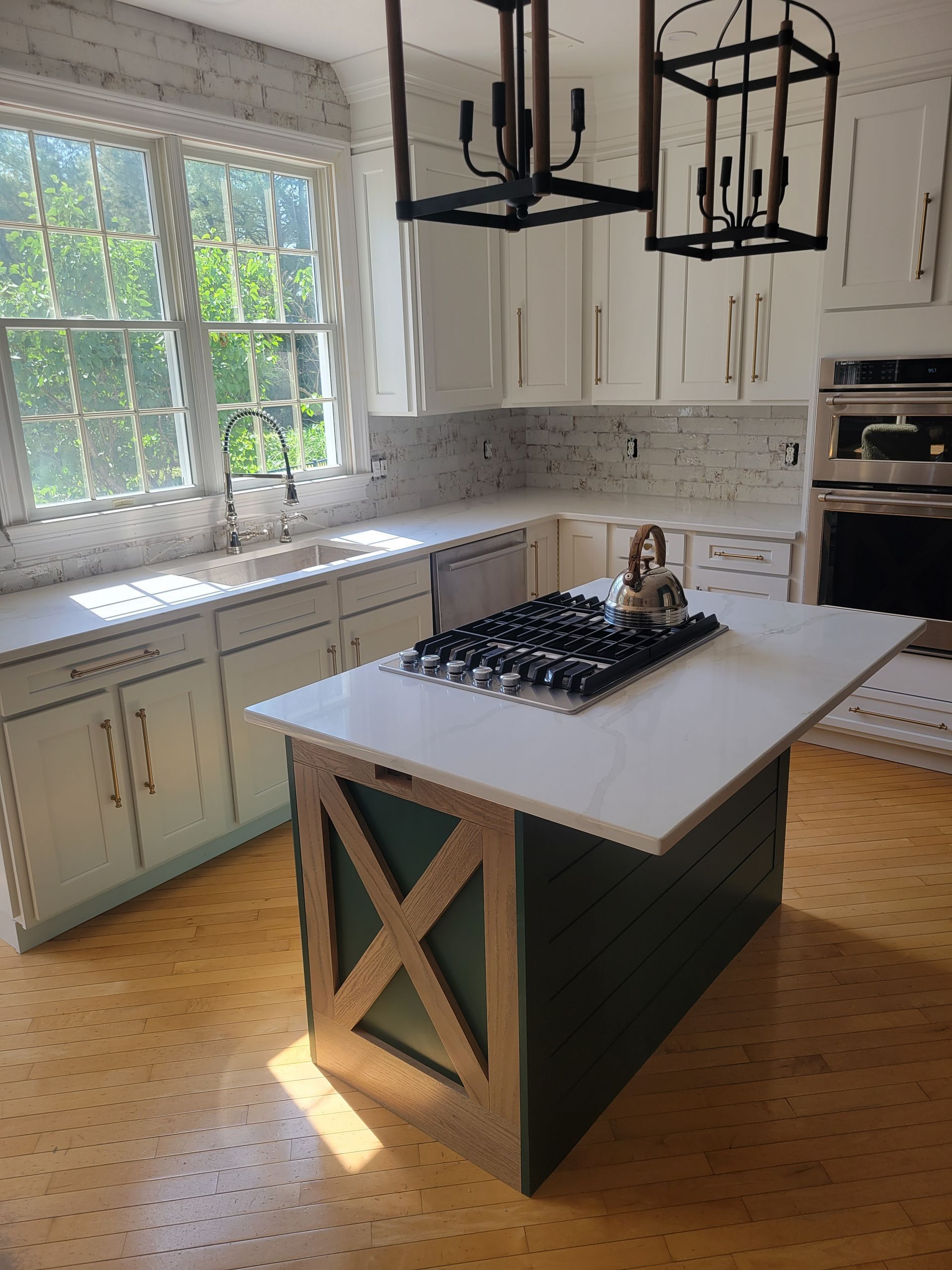 A kitchen with white cabinets and a large island with a stove top oven.