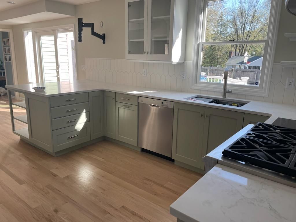 A kitchen with white cabinets, a stove, a sink, and a window.