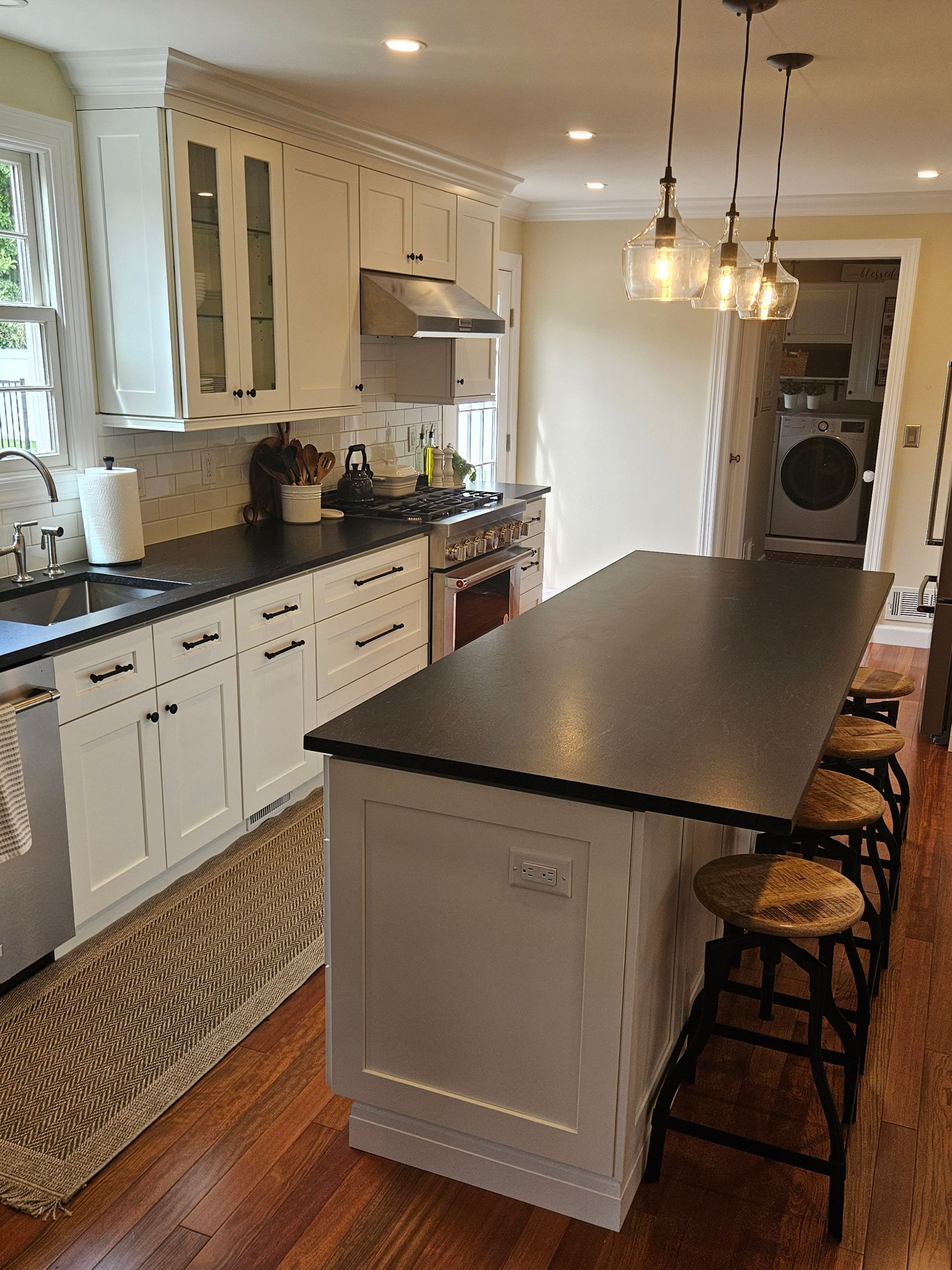 A kitchen with white cabinets and black counter tops