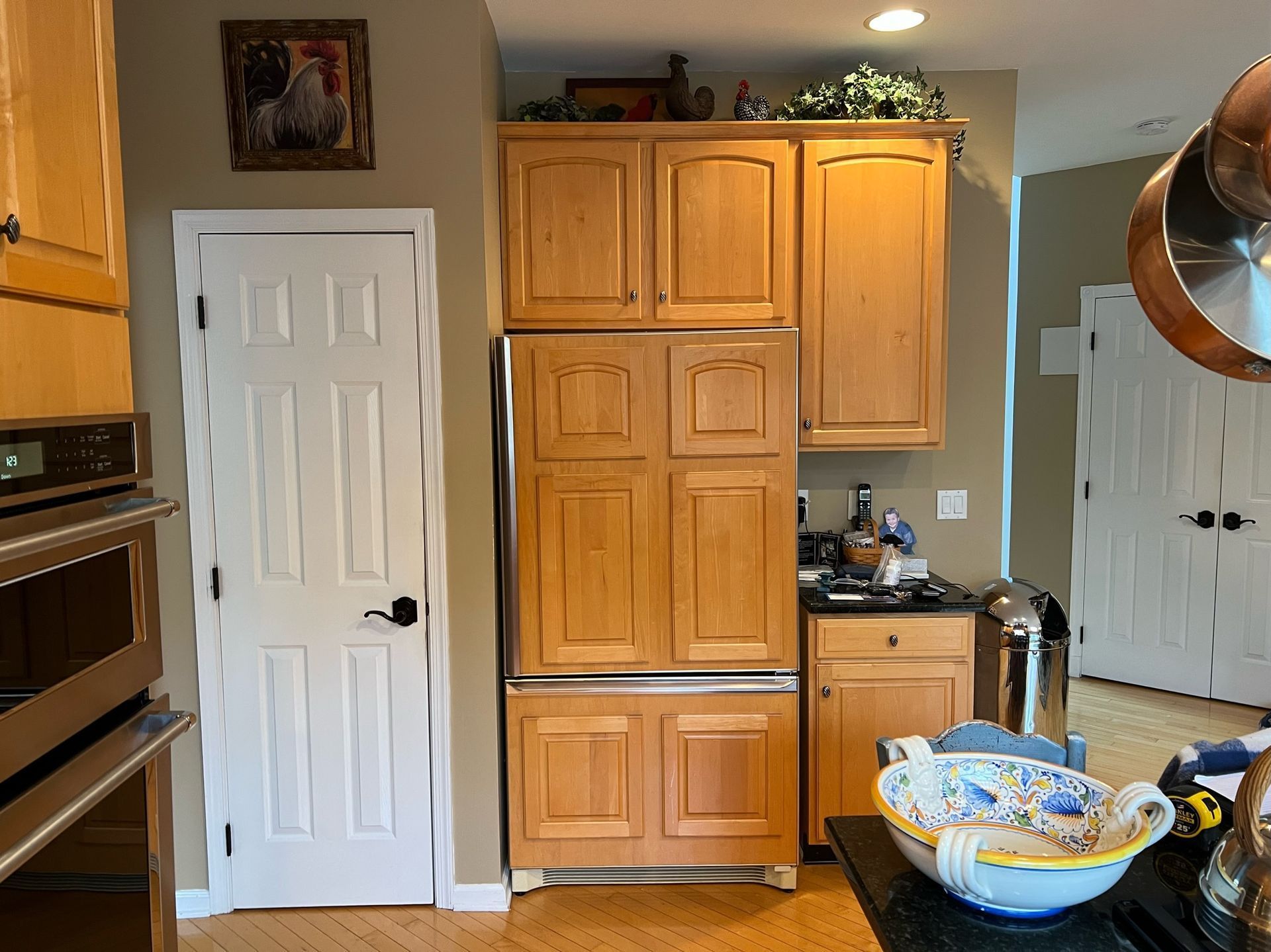 A kitchen with wooden cabinets and a stainless steel refrigerator - before