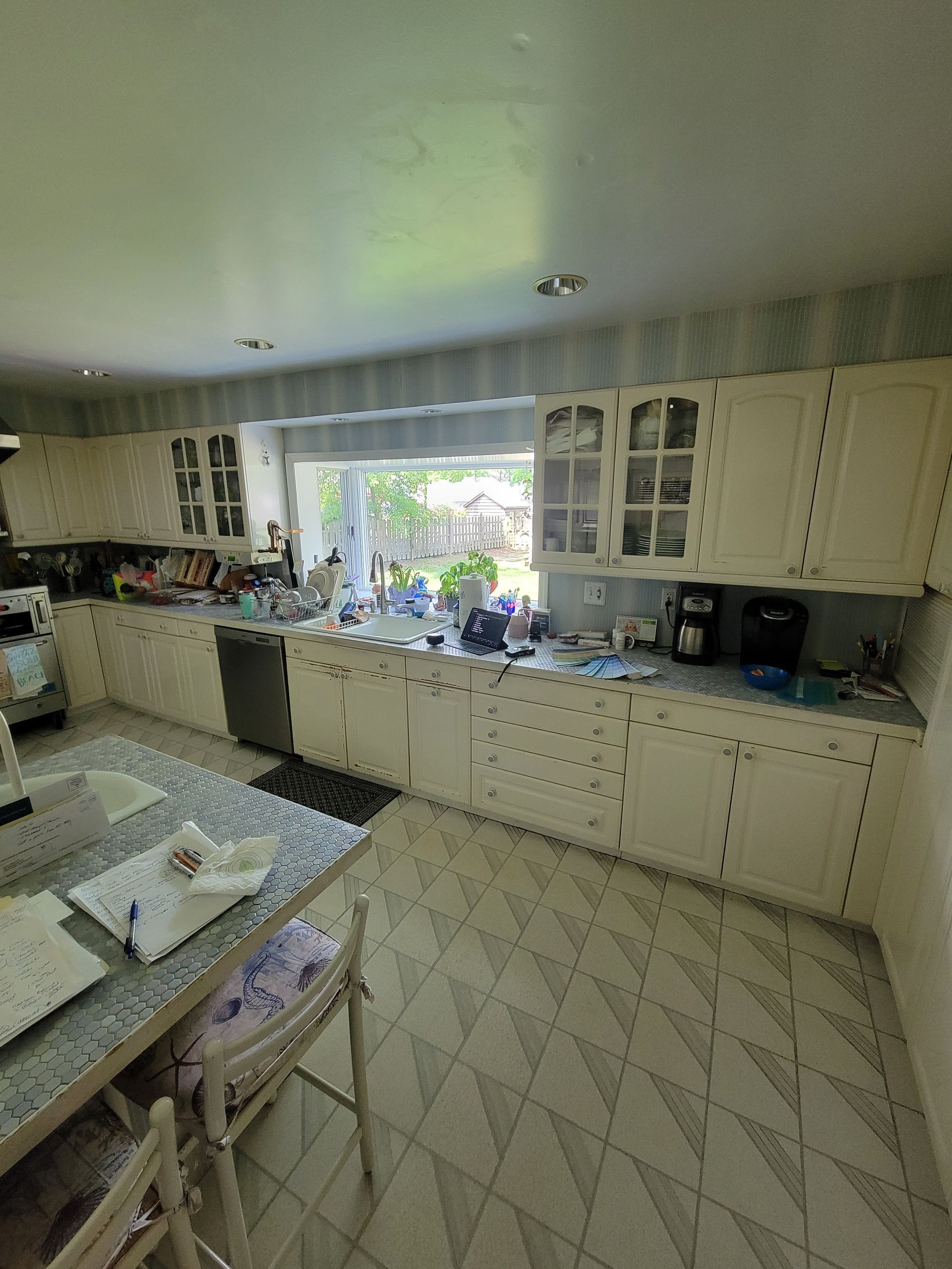 A kitchen with a table and chairs and a large window.