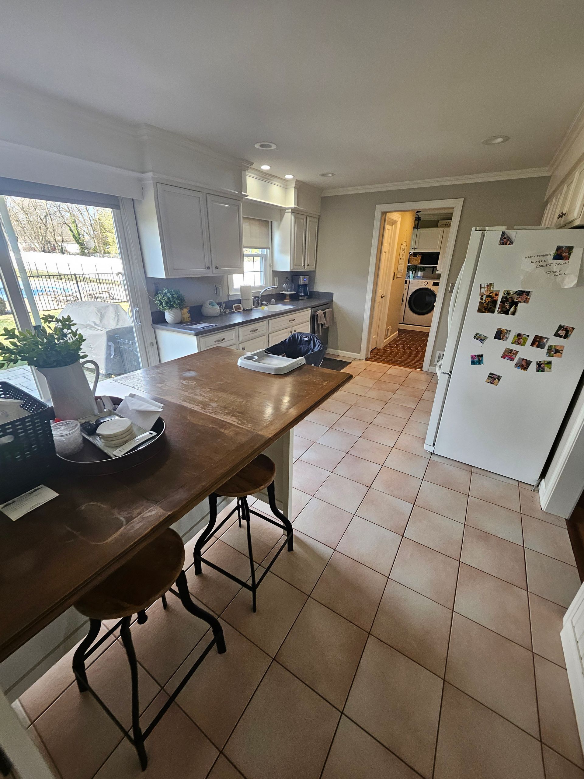 A kitchen with a table and stools and a refrigerator.