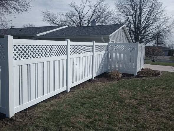 White vinyl fence with lattice panels along a grassy yard beside a house