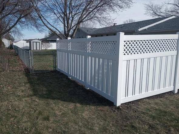 White vinyl privacy fence with lattice top in a grassy backyard under a leafless tree
