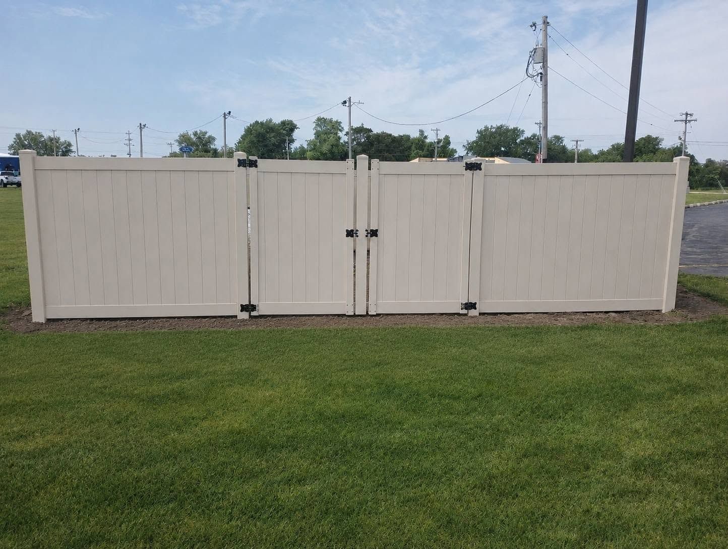 White vinyl fence gates on a grassy lawn under a cloudy sky
