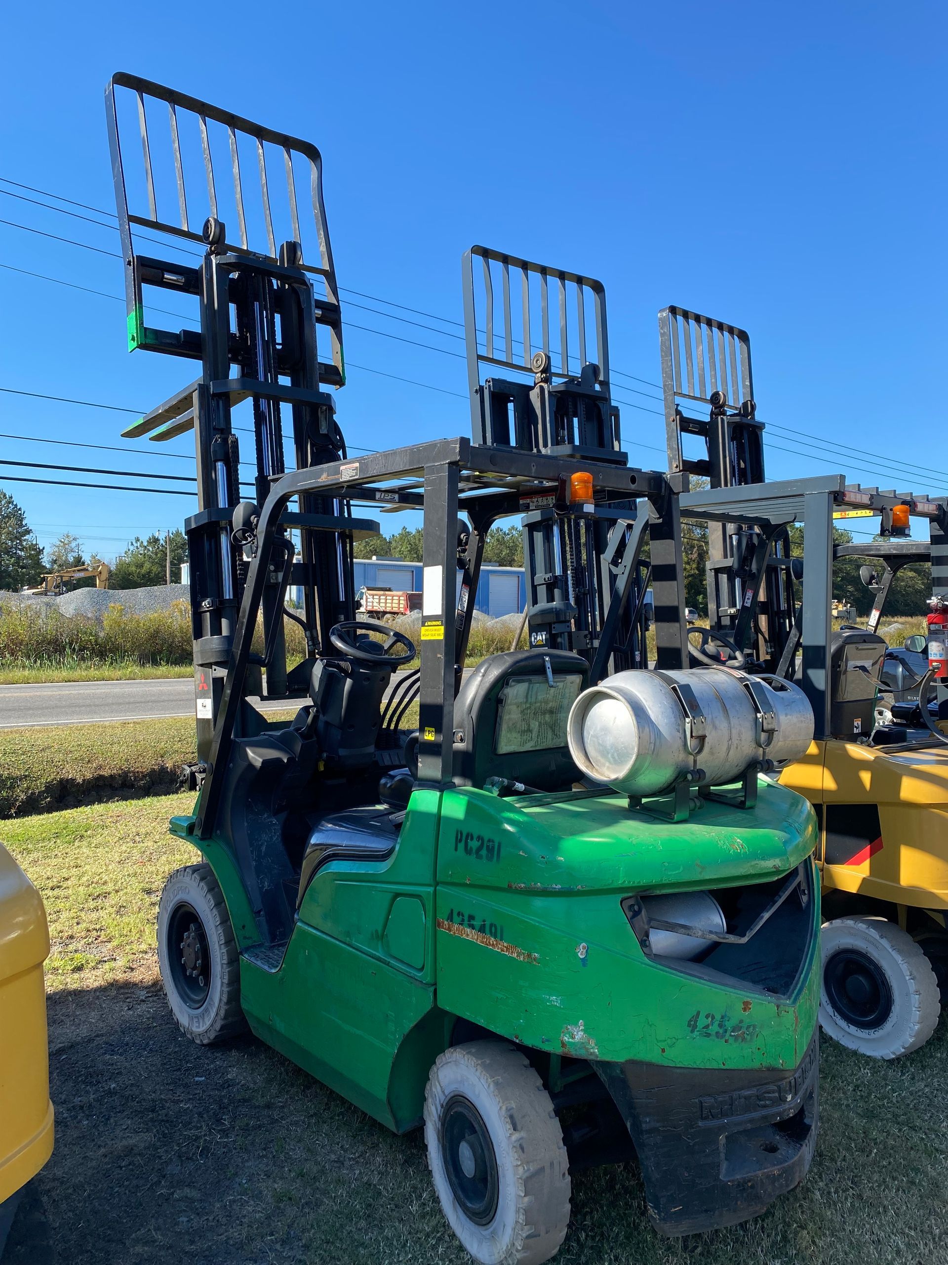 A green forklift with a propane tank on top of it.