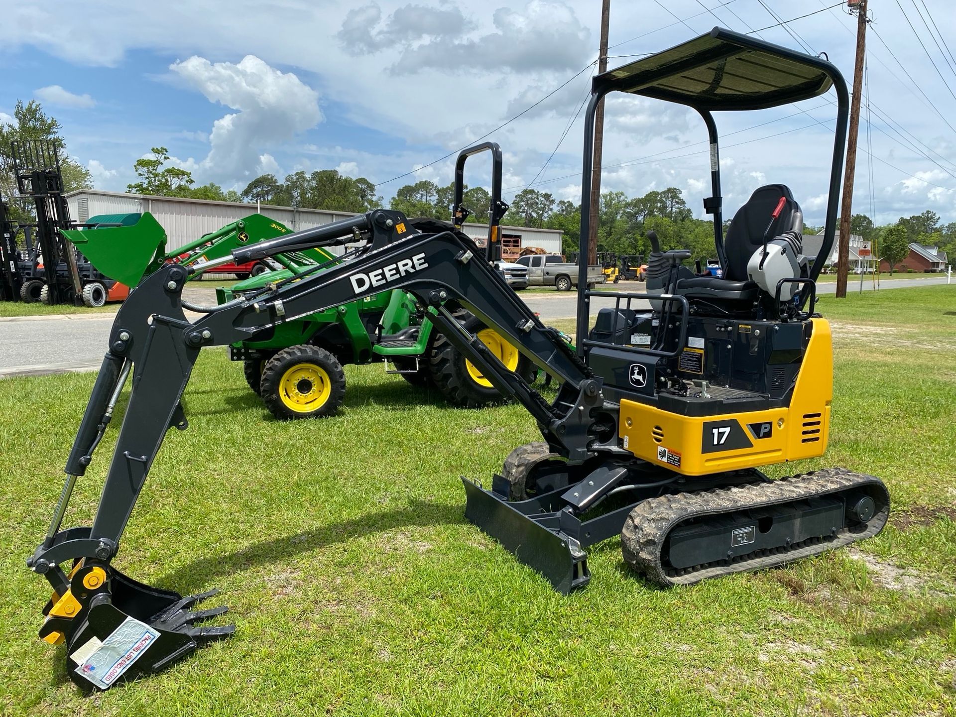 A small excavator is parked in the grass next to a tractor.