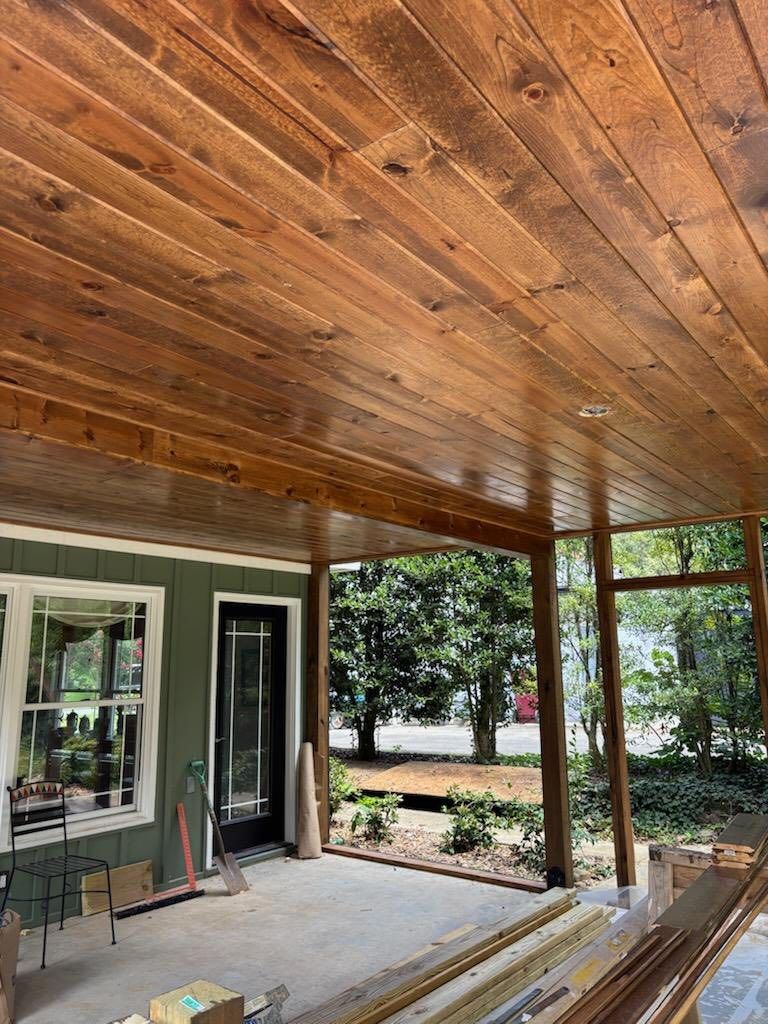 Wooden ceiling on a covered porch. View of a house, door, windows, and trees.